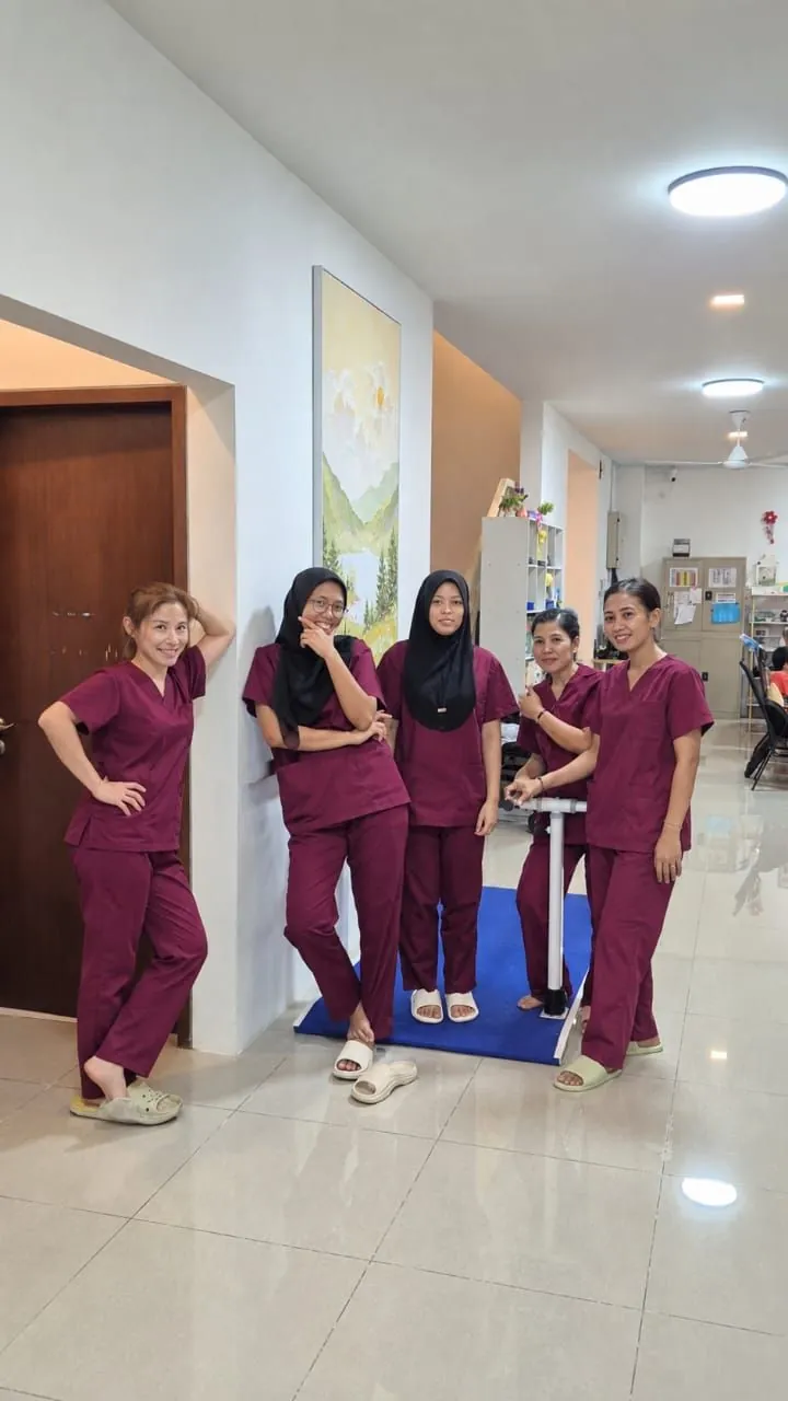 Five IROHA caretakers in maroon uniforms in the hallway
